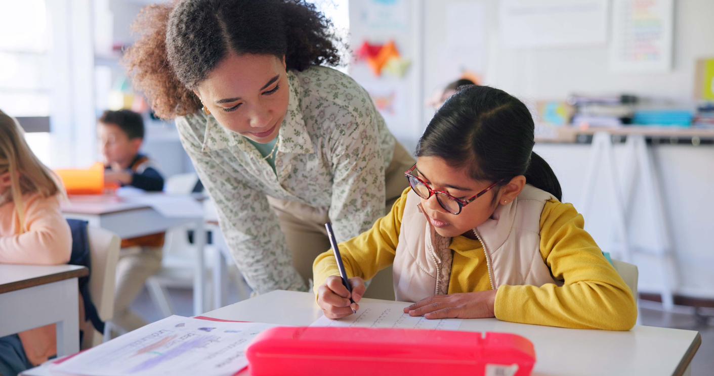A Special Education Teacher Works With a Student at a Desk..jpg