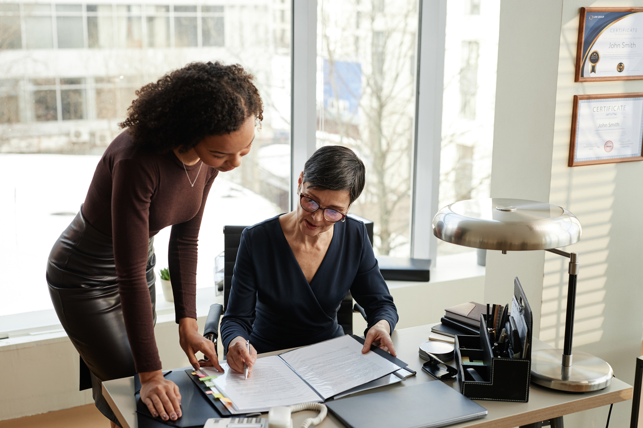 A Legal Assistant and an Attorney Look Over a Document in an Office.
