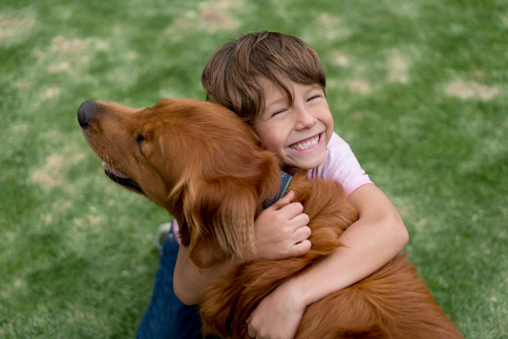 A smiling child hugs a dog.