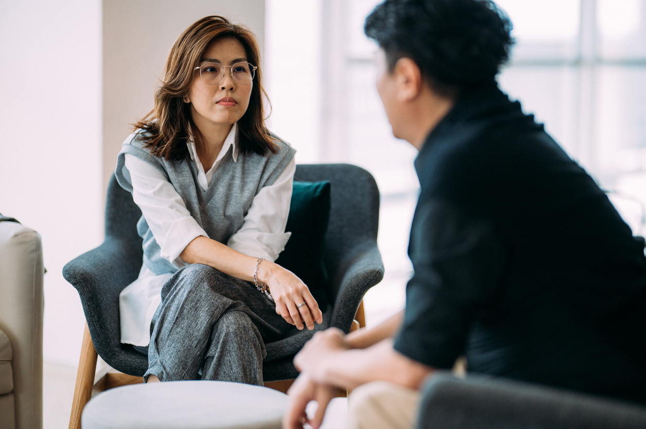 An Addiction Counselor Sitting in a Chair Listens to a Client.