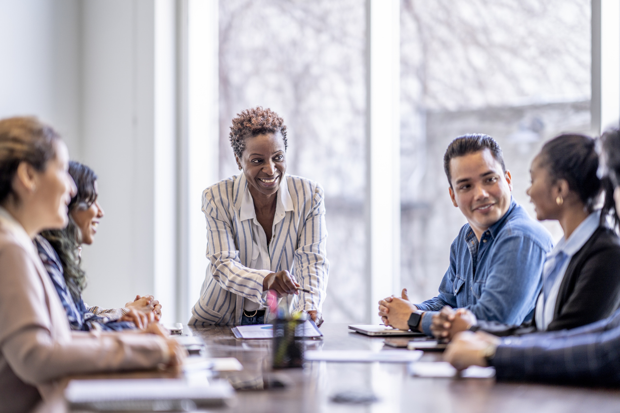 A team leader chairs a business meeting at a conference table.