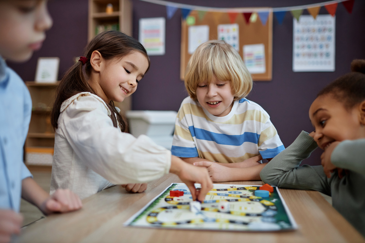 A group of kindergarten students play a board game in a classroom.