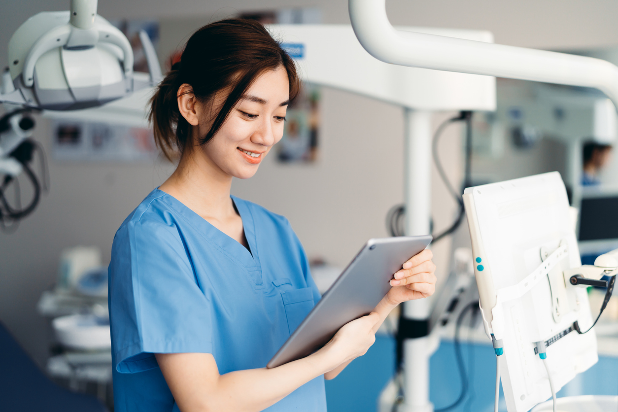 A Nurse Works on a Tablet in a Hospital Room.