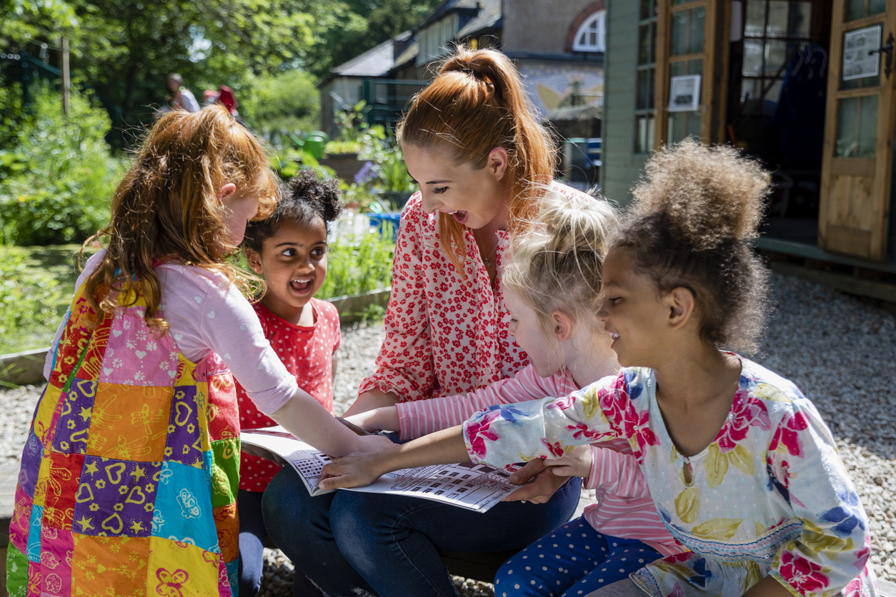 A Summer School Teacher Sits Outside With Students and Reads a Book