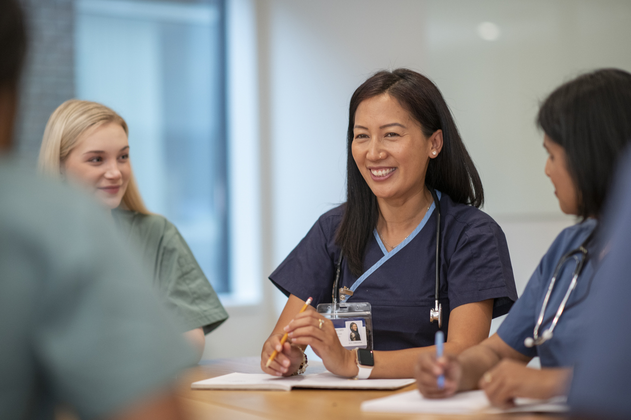 A nurse leader meets with the nursing team at a table.