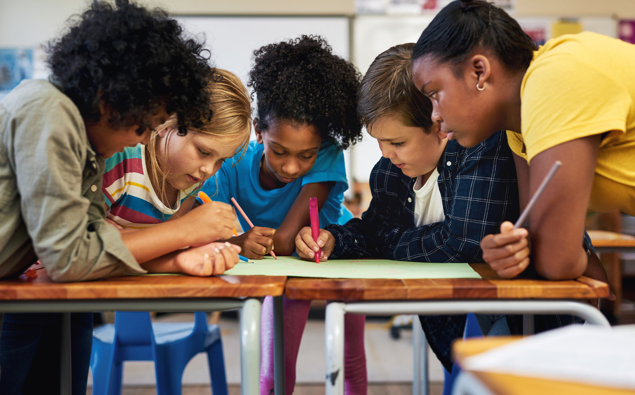 Five Students Stand Around a Table and Work on a Group Project.