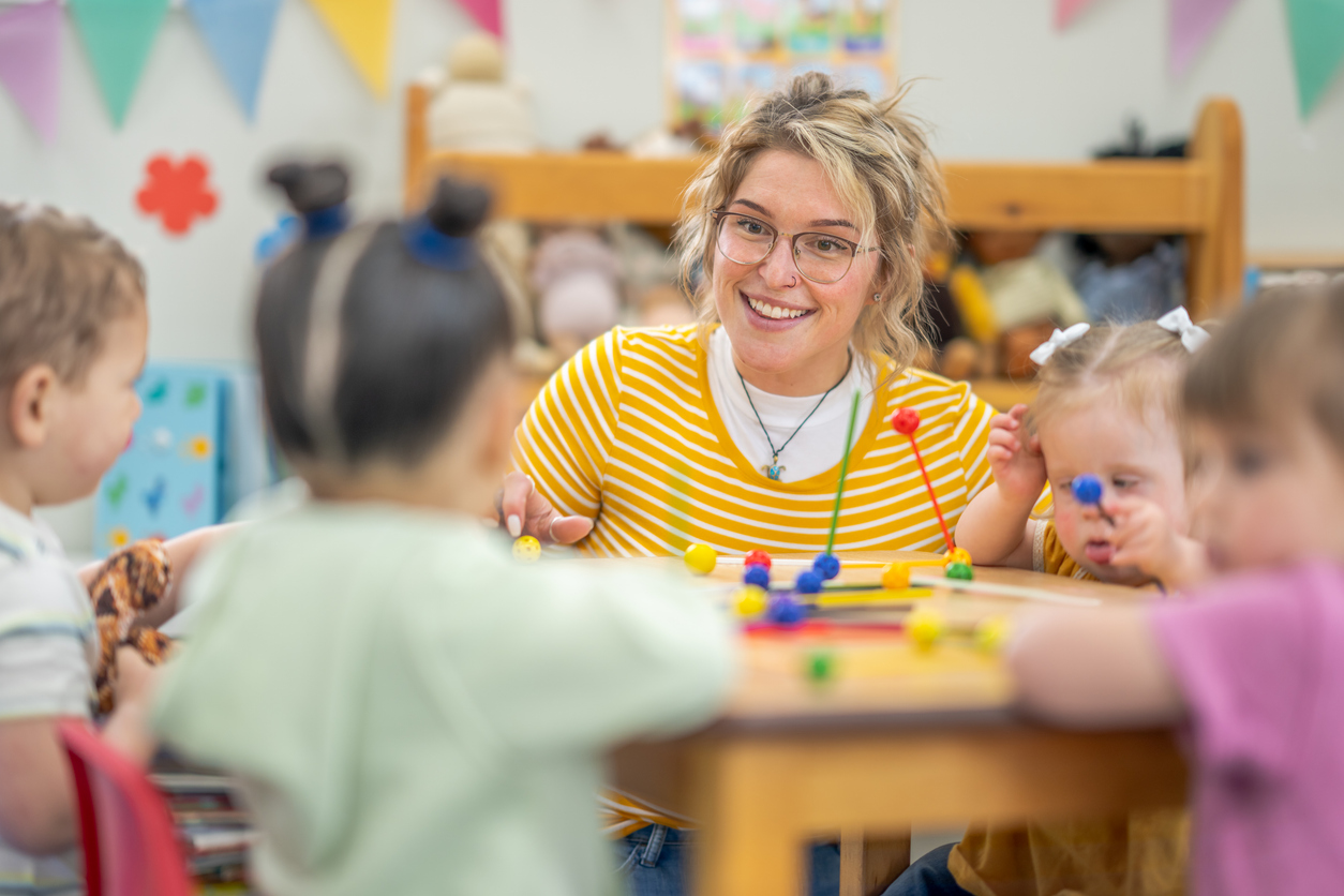 A special education teacher sits at a table with four students.
