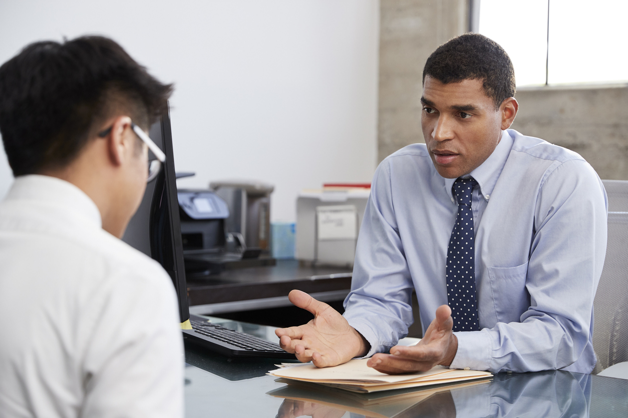 A Correctional Treatment Specialist Seated at a Desk Talks With a Client.