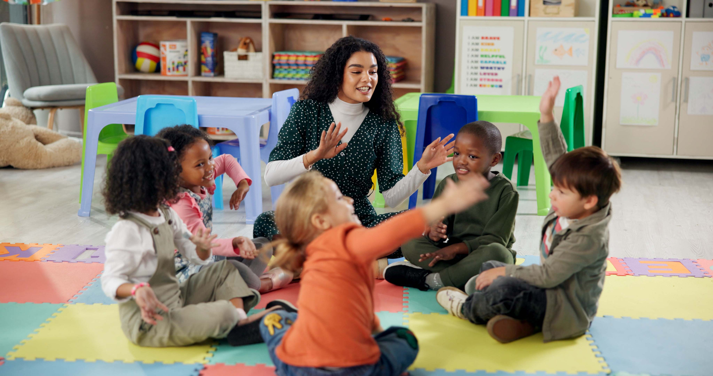 A Childcare Administrator Plays With a Group of Children on a Classroom Floor.