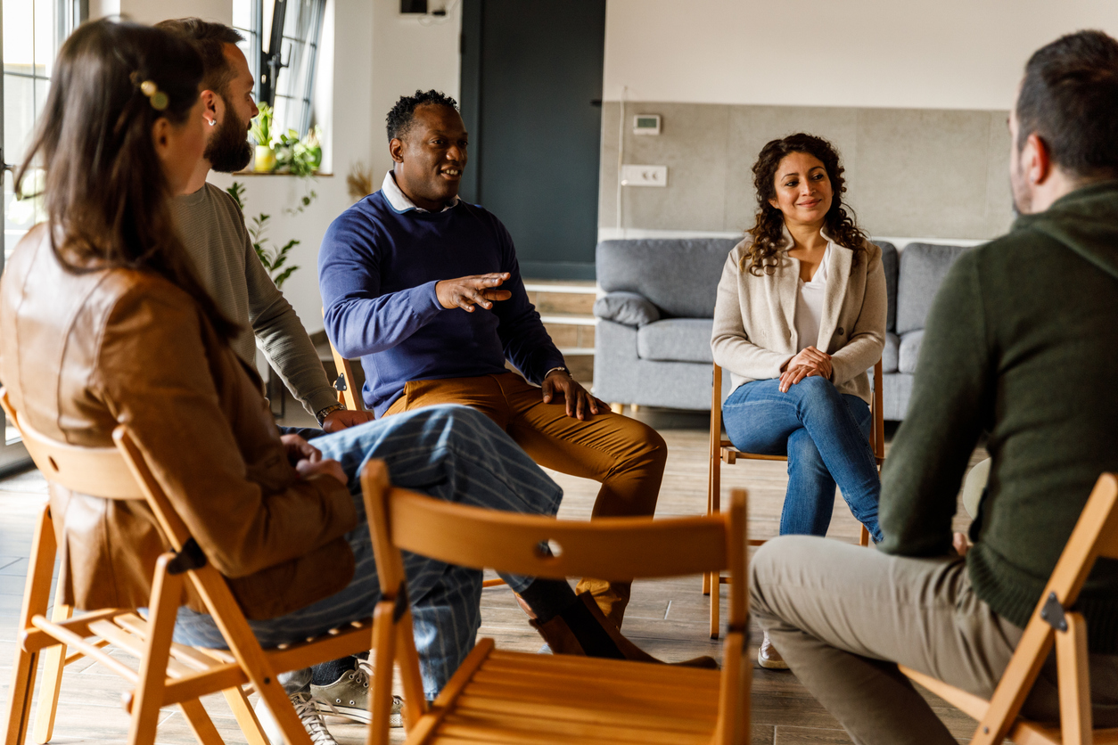 A group of people talk during a group therapy session.