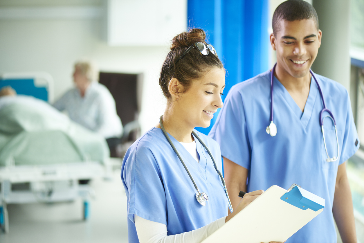 A charge nurse meets with another nurse in a hospital room. 