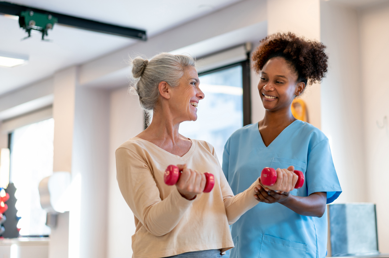 A Nurse Health Coach Guides a Patient Who Is Working out With Dumbbells.