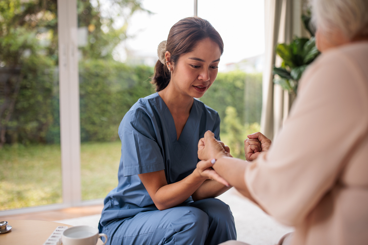 A nurse holds a patient’s hands during a breathing exercise.