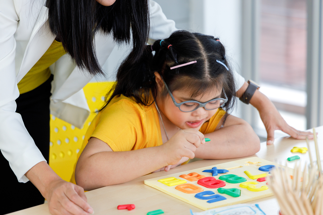 A Special Education Teacher Helps a Student With a Puzzle.
