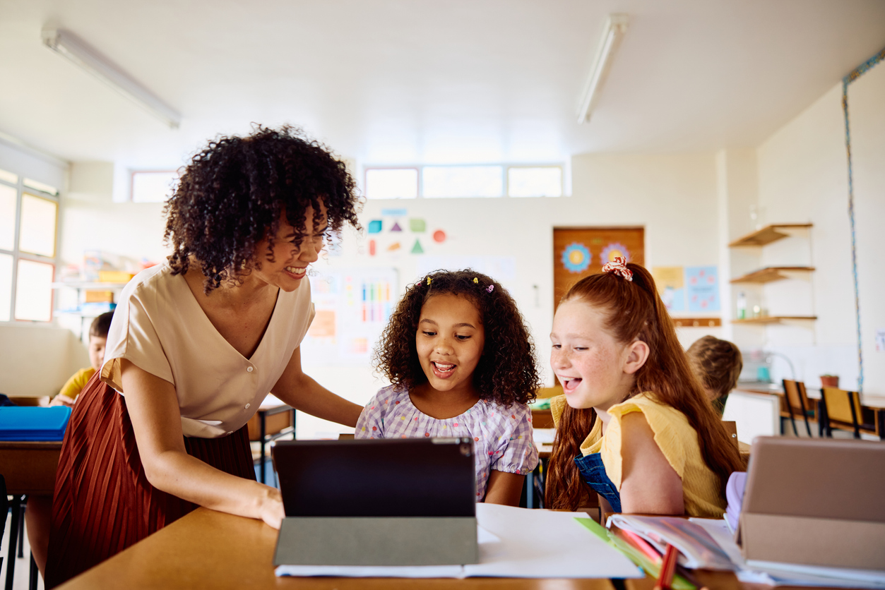 A Teacher Uses a Tablet to Engage With Young Students.