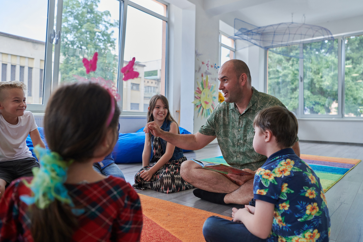 A Special Education Teacher Sits With Students on the Floor and Reads Them a Book.