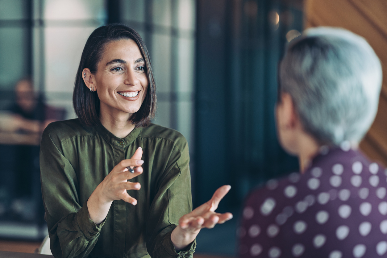 A Smiling Business Leader and Their Employee Have a Conversation in an Office.